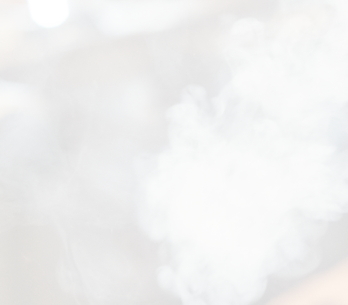 An adult is lighting a cigar with a lighter while another adult stands in the background wearing a white turtleneck.

Description generated by AI